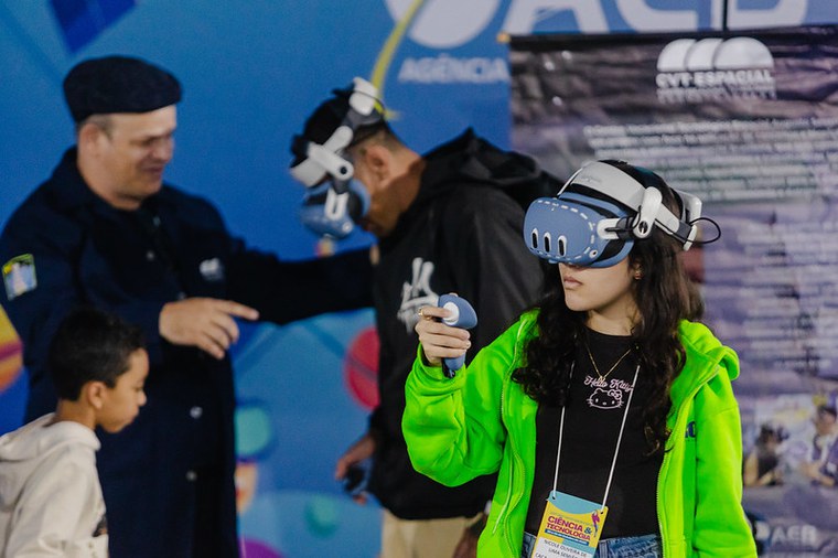 Astrônoma Nicolinha com óculos de realidade virtual no estande da AEB. Foto: MCTI