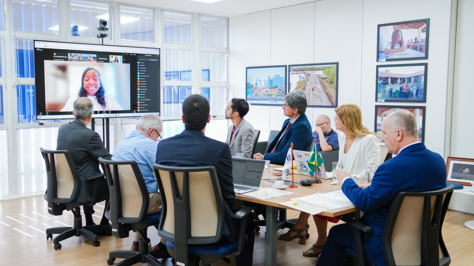 Representantes da AEB ao redor da mesa de reunião. Representantes da AfSA na tela de tv ao centro da imagem
