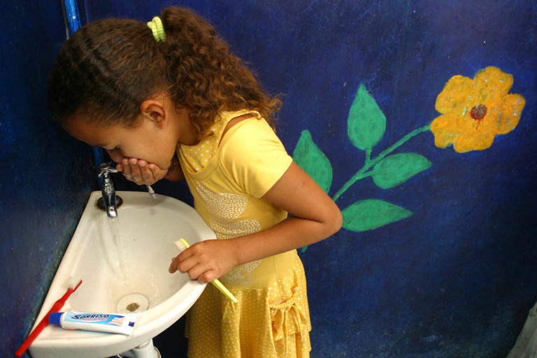 Criança usando água para escovar os dentes