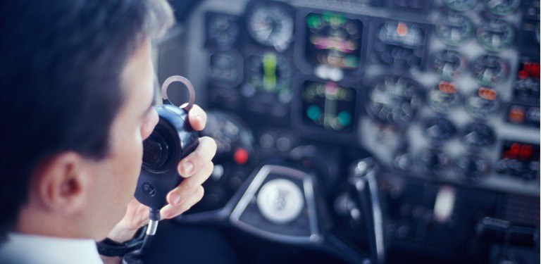 Piloto utilizando equipamento de comunicação em uma aeronave