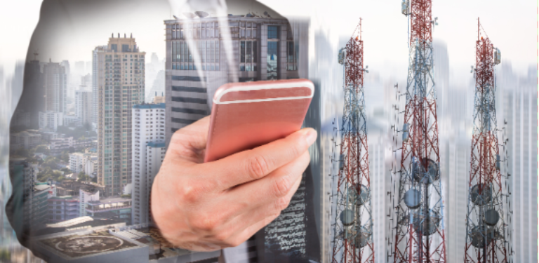 Homem com celular e antenas móveis ao fundo