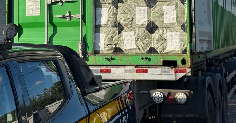 Caminhão com carga de microfones sem fio apreendida durante blitz, ao lado de viatura da PRF.