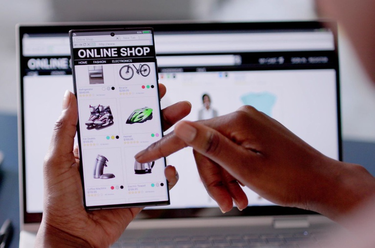 Pessoa faz compras online usando smartphone e notebook