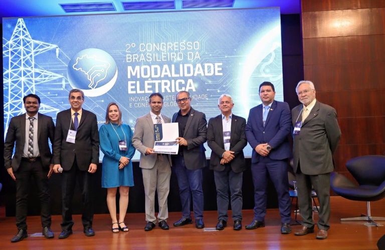 Imagem mostra grupo de pessoas em um palco e ao centro o gerente Renato Bizerra