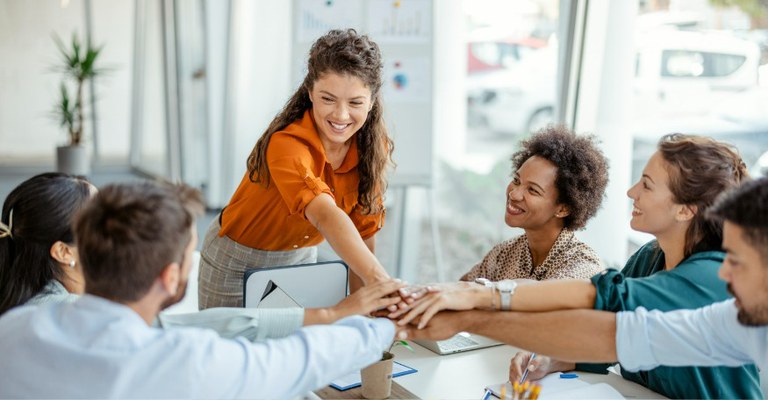 Pessoas ao redor de uma mesa dão as mãos