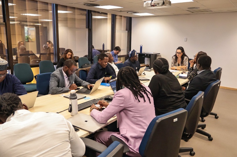 Pessoas em sala de reunião discutem assuntos relacionados a telecomunicações