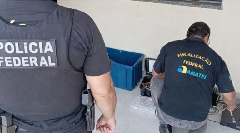 Agente da Polícia Federal e servidor da Anatel observam os materiais da estação ilegal de rádio