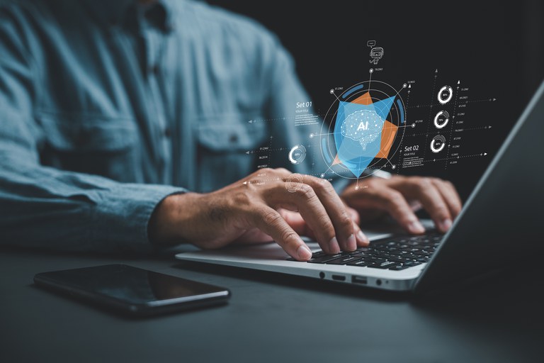 Foto de stock de A IA ajuda a gerar negócios com automação inteligente e um sistema BPA, enquanto um empresário em sua mesa usa um laptop para dar instruções à IA, conduzindo a automação de processos com eficiência