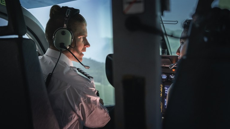 Instrutor conversando com aluno dentro da cabine de um simulador de helicóptero.