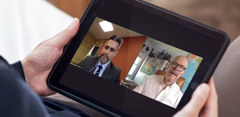 Mulher assiste no laptop ao Presidente da Anatel, Leonardo de Morais, (à esquerda no vídeo do aparelho) durante fala na DAS 2021 Global Summit