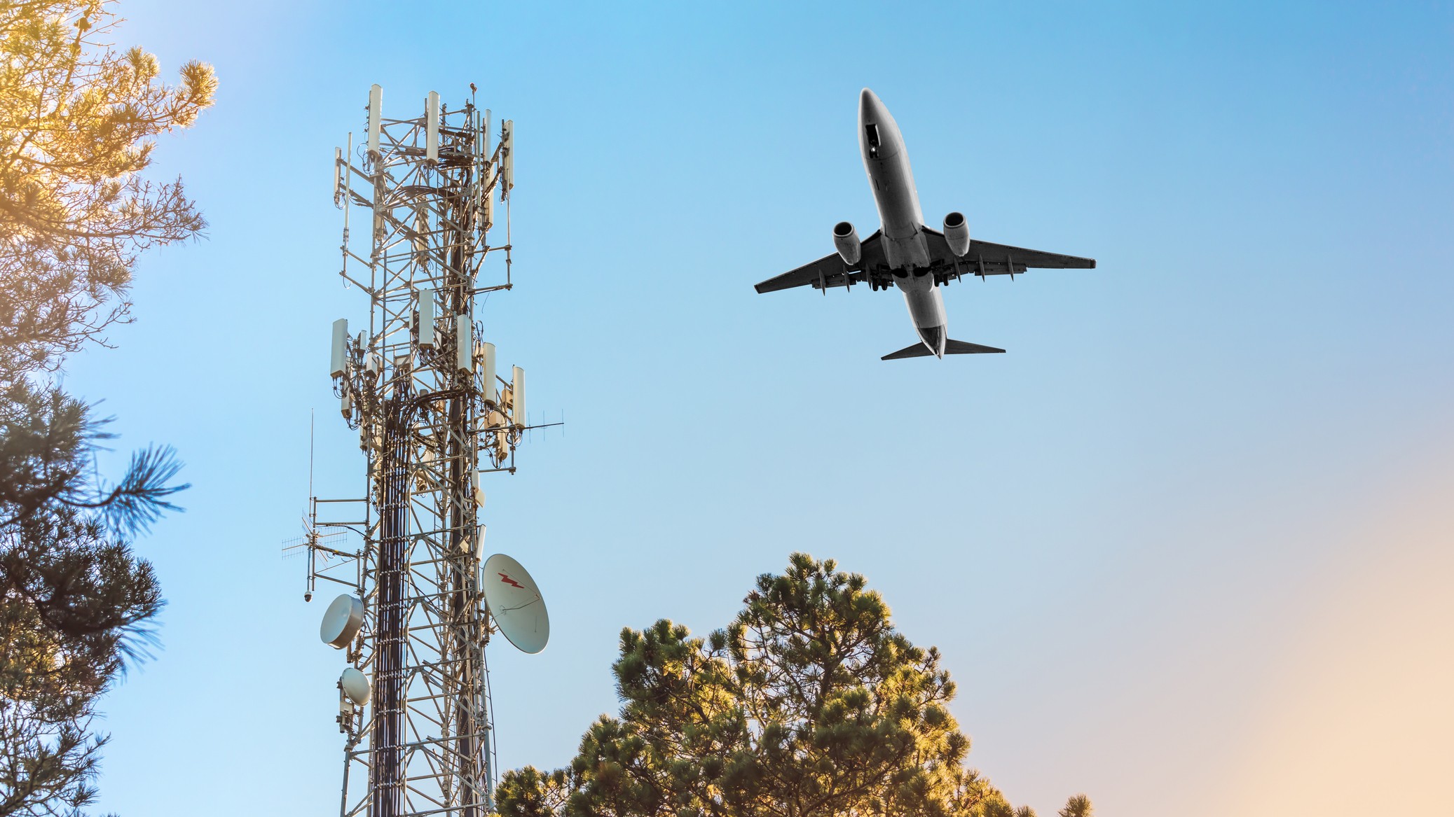 Torre de celular 5G com avião sobrevoando. Conceito de interferência de altitude perigosa para pouso.