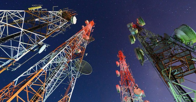 A imagem mostra várias torres de telecomunicação sob um céu noturno.