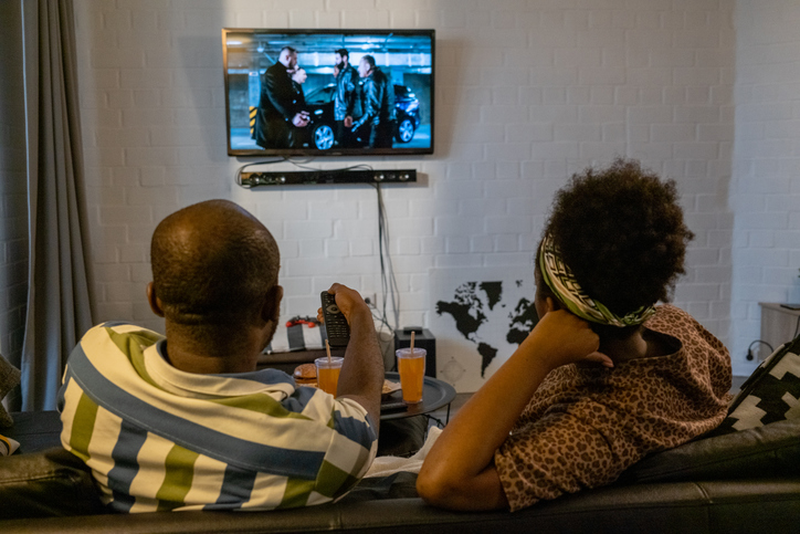 Pessoas assistem a televisão em sala
