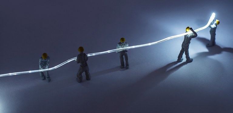 Imagem ilustrativa representa uma fibra óptica sendo carregada, tanto a destacar a importância da infraestrutura como a representar a soma dos diversos esforços a ampliar a conectividade no país