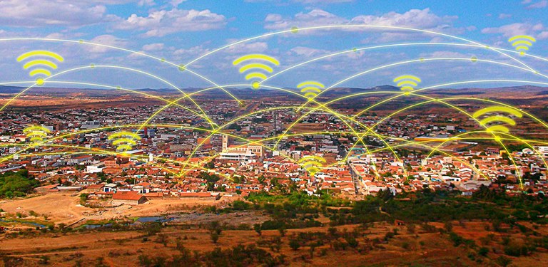 Imagem apresenta uma cidade com acesso à banda larga, representada por linhas amarelas e pelo símbolo do serviço que conecta casas e demais equipamentos urbanos