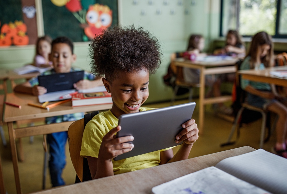 Foto mostra alunos em sala de aula utilizando tablets.