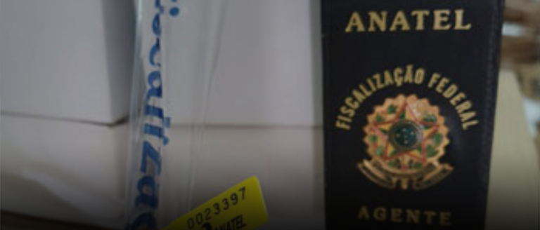 Carteira com símbolo da Fiscalização da Anatel e produtos apreendidos