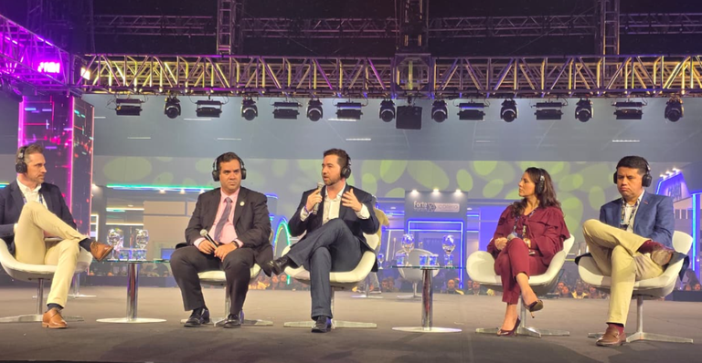 iMAGEM MOSTRA PESSOAS SENTADAS DEBATENDO EM UM PALCO