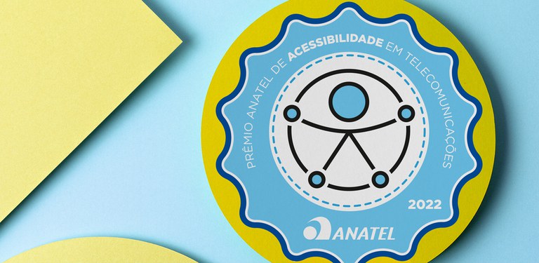 Imagem ilustrativa em tons de amarelo e azul do prêmio de acessibilidade, em que se lê "Prêmio Anatel de Acessibilidade em Telecomunicações 2022 -Anatel"