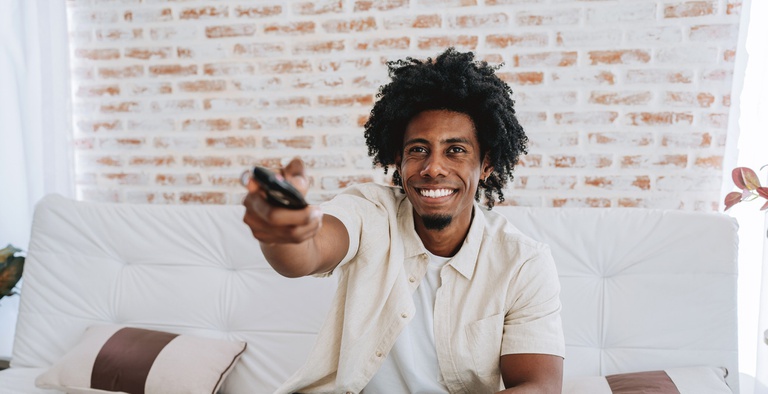 Rapaz aponta controle remoto para a televisão