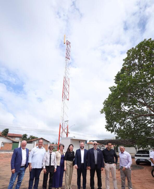 Grupo de pessoas se posiciona em frente à antena da estação  