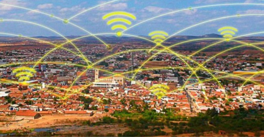 Imagem de uma cidade vista do alto com ícones de sinal Wi-Fi conectando diferentes pontos, representando uma rede de internet sem fio cobrindo toda a área urbana.