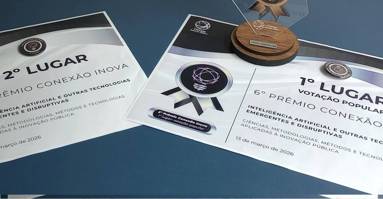 Imagem mostra os prêmios conquistados pelo projeto SEI IA da Anatel no 6º Prêmio Conexão Inova. Sobre uma mesa azul, aparecem dois certificados impressos: um indica o 2º lugar na categoria “Inteligência Artificial e Outras Tecnologias Emergentes e Disruptivas” e o outro registra o 1º lugar na votação popular. Ao fundo e parcialmente sobre os certificados, há um troféu com base de madeira e placa transparente com a indicação “Voto Popular”. A imagem representa o reconhecimento público e técnico do SEI IA no evento.