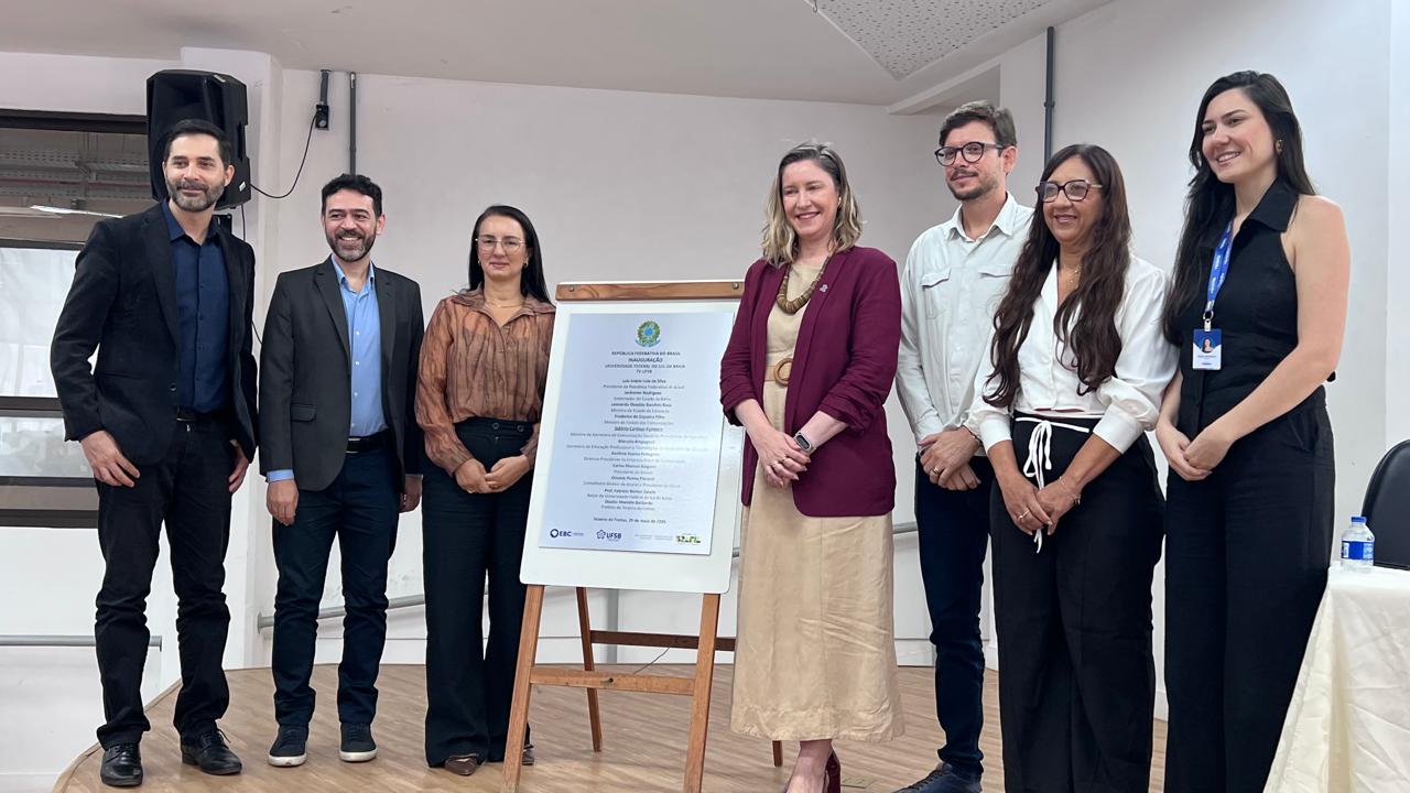 Imagem mostra sete pessoas, três do lado esquerdo e quatro do direito, com a placa de inauguração no meio