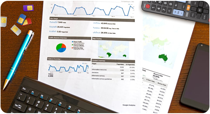 Imagem com uma mesa com chips de celular, papéis com gráficos, caneta, calculadora e celular.
