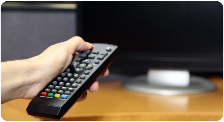 Mão com controle remoto em frente a TV de tela plana
