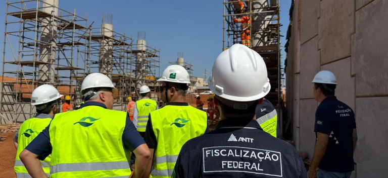 IMAGEM DE HOMENS NA OBRA COM CAPACETE  DE OBRA E BLUSAS AMARELAS