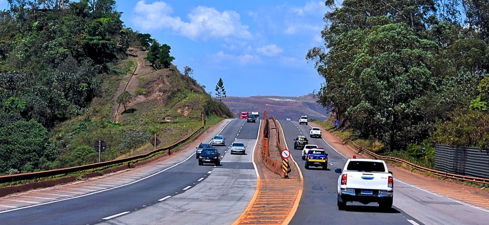 IMAGEM COM CARROS NA RODOVIA E AO LADO AREA VERDE