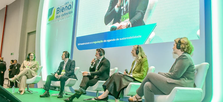 IMAGEM COM 5 PESSOAS, AO FUNDO TEM UM PAINEL