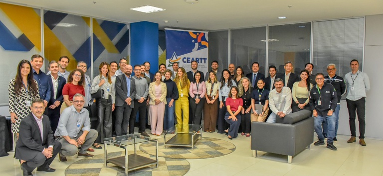 IMAGEM COM VARIAS PESSOAS, DENTRO DE UMA SALA POSANDO PARA A FOTO