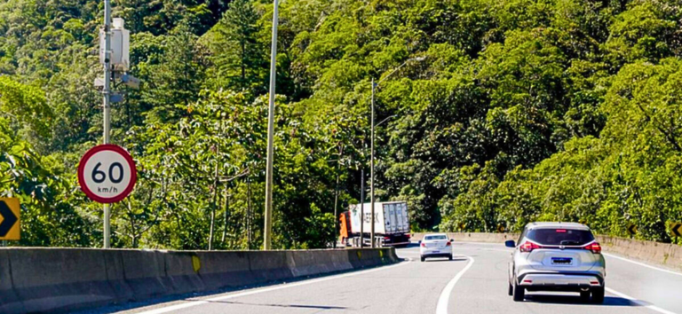FOTO DA RODOVIA COM UM CARRO E UMA PLACA DE SINALIZAÇÃO