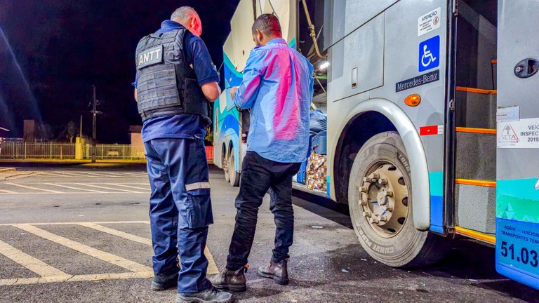 IMAGEM COM DOIS HOMENS DE FRENTE PARA UM ONIBUS