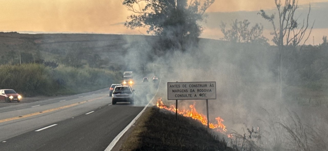 IMAGEM COM FOGO PERTO DA RODOVIA E UMA CARRO PASSANDO