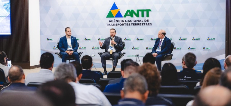 Foto mostrando diretor da ANTT, superintendente da ANTT e diretor da ABRC na mesa de abertura do evento
