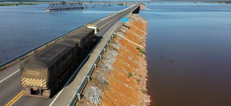 Foto mostrando rodovia passando por cima do rio e carreta