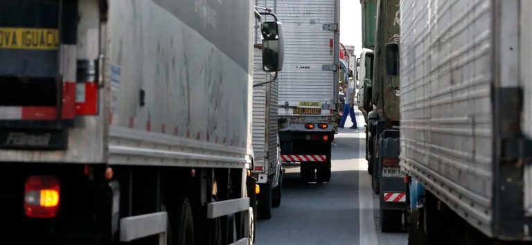 Foto mostrando vários caminhões com cargas em rodovia