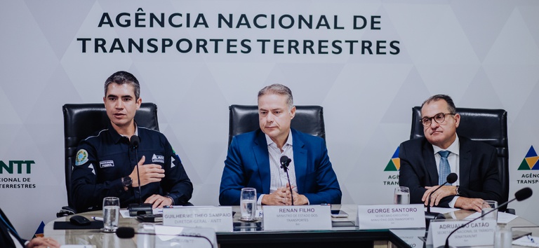 Foto mostrando diretor-geral da ANTT e ministro dos transportes em mesa com jornalistas