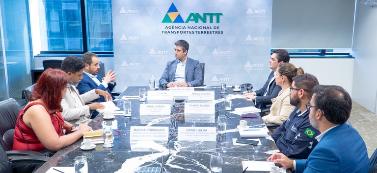 Foto com diretor da ANTT, presidente da Sinagências e demais representantes sentados à mesa na reunião