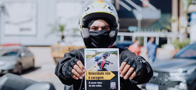 IMAGEM DE UM MOTOCICLISTA SEGURANDO UM FLYER DA CAMPANHA
