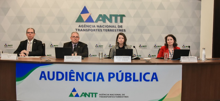 IMAGEM DE QUATRO PESSOAS SENTADAS EM UMA BANCADA, NA AUDIENCIA PUBLICA