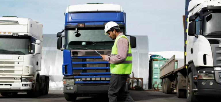Foto mostrando fiscal andando na frente de caminhões de carga
