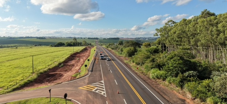IMAGEM DE UMA RODOVIA COM BIFURCAÇÃO COM SINALIZAÇÃO DE SOLO E CARROS PASSANDO