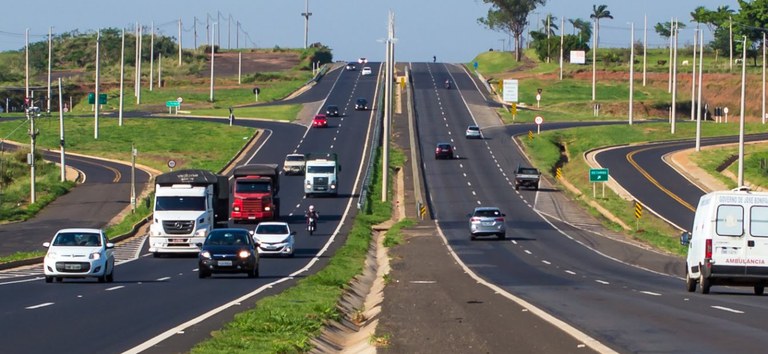 Foto mostrando rodovia bem pavimentada com movimento de carros e ônibus