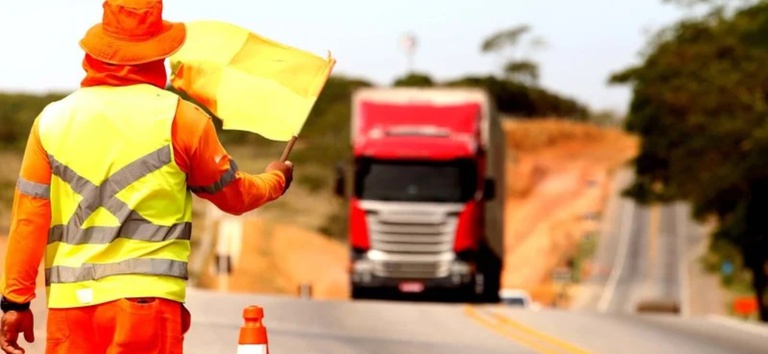 Homens na rodovia sinalizando obras