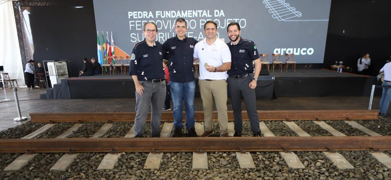 Foto com delegação da ANTT e secretário nacional de transporte ferroviário em cima do trecho e da pedra fundamental da primeira autorização ferroviária do Brasil