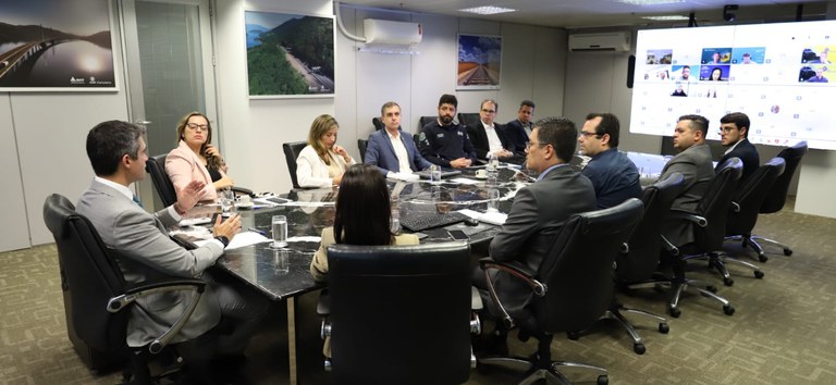 Foto mostrando comitê climático reunido presencialmente e online